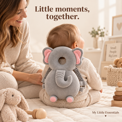 Elephant cushion backpack worn by an awake seated baby with a parent beside them